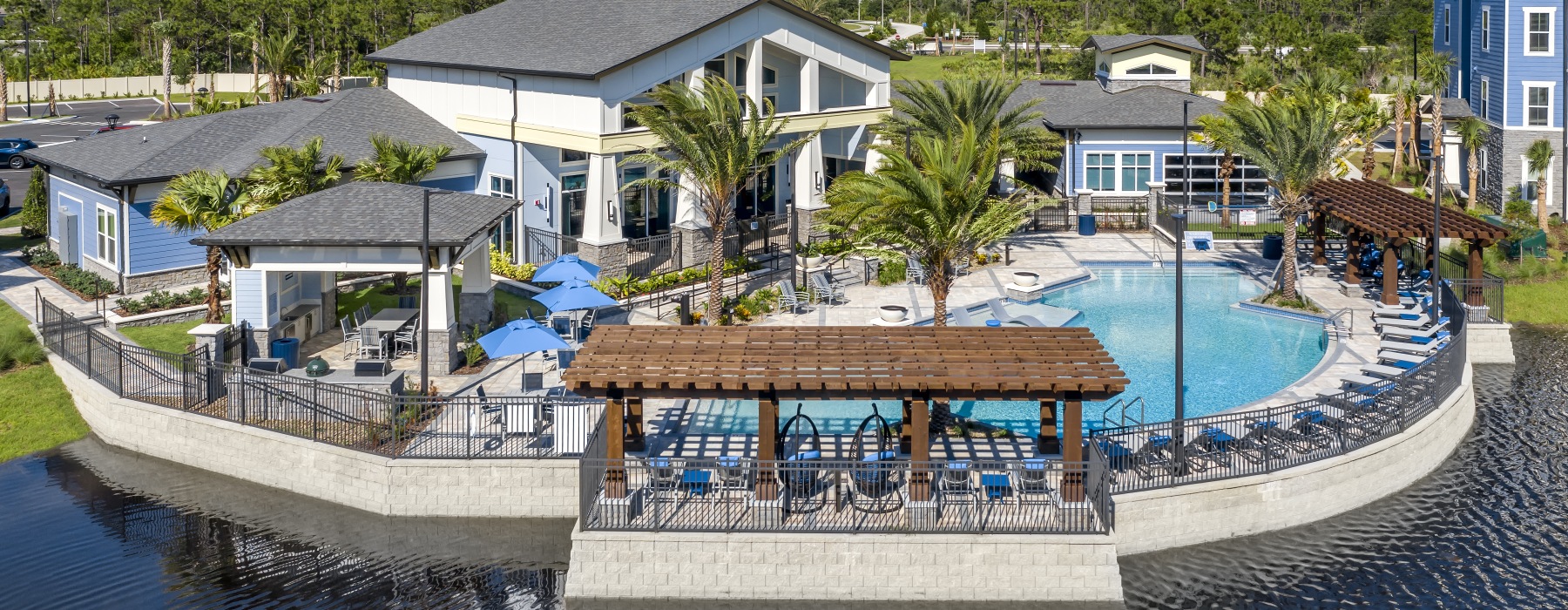 Resort-style pool and clubhouse at Addison Pointe apartments in Melbourne, Florida, featuring lounge seating, palm trees, and outdoor amenities.